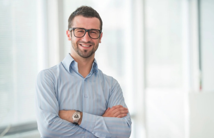 uomo giovane sorridente con le braccia incrociate
