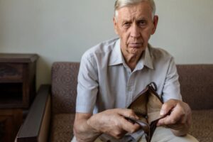 uomo anziano che mostra un portafoglio vuoto