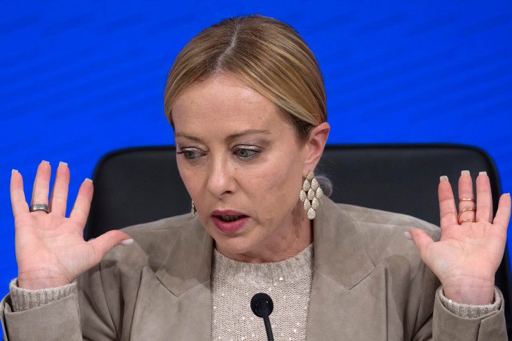 il premier giorgia meloni alza le mani mentre parla al microfono