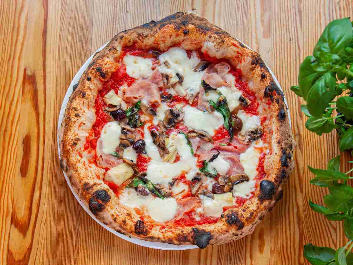 una pizza con prosciutto, olive, funghi